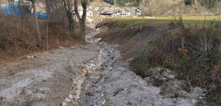 Ureditev struge Dovškega potoka ob regionalni cesti na Dovjem; oblaganje s kamnom v brežino struge.